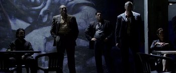 Movie still from “Miami Vice” (2006), directed by Michael Mann – A group of men standing next to each other in front of a wall; Wide shot, Low angle