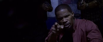 Movie still from “Miami Vice” (2006), directed by Michael Mann – A man in a red shirt is pointing at the camera; Close Up shot, Over the shoulder angle