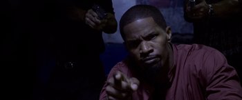 Movie still from “Miami Vice” (2006), directed by Michael Mann – A man in a red shirt is pointing at the camera; Close Up shot, Over the shoulder angle