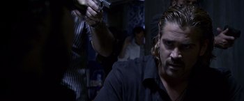 Movie still from “Miami Vice” (2006), directed by Michael Mann – A man holding a gun in a room with other people; Close Up shot, Over the shoulder angle