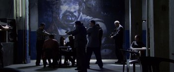 Movie still from “Miami Vice” (2006), directed by Michael Mann – A group of people standing in front of a painting; Wide shot, Over the shoulder angle