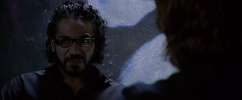 Movie still from “Miami Vice” (2006), directed by Michael Mann – A man with curly hair and glasses talking to another man; Close Up shot, Over the shoulder angle