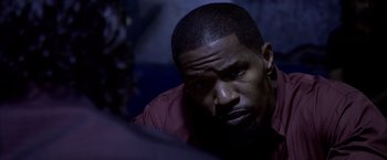 Movie still from “Miami Vice” (2006), directed by Michael Mann – A person sitting down with his head down; Close Up shot, Over the shoulder angle