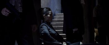 Movie still from “Miami Vice” (2006), directed by Michael Mann – A woman sitting in a chair in front of a staircase; Medium shot, High angle