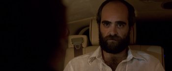 Movie still from “Miami Vice” (2006), directed by Michael Mann – A bearded man sitting in the back seat of a car; Close Up shot, Over the shoulder angle