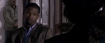 Movie still from “Miami Vice” (2006), directed by Michael Mann – A man wearing a suit and tie in front of another man; Close Up shot, Over the shoulder angle