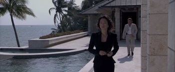 Movie still from “Miami Vice” (2006), directed by Michael Mann – A woman in a black suit standing in front of a pool; Wide shot, High angle