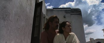 Movie still from “Miami Vice” (2006), directed by Michael Mann – A man and a woman sitting next to each other outside; Medium shot, Low angle