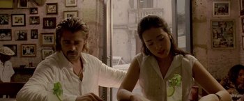 Movie still from “Miami Vice” (2006), directed by Michael Mann – A man and a woman sitting at a table in front of an open window; Medium shot, Over the shoulder angle