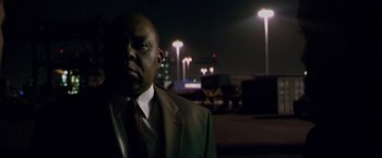 Movie still from “Miami Vice” (2006), directed by Michael Mann – A man wearing a suit and tie standing in a parking lot at night; Close Up shot, Low angle