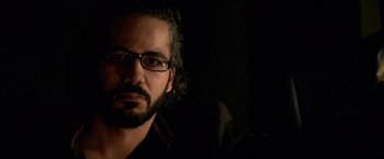 Movie still from “Miami Vice” (2006), directed by Michael Mann – A person wearing glasses and a black shirt; Close Up shot, Low angle