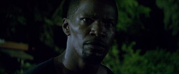 Movie still from “Miami Vice” (2006), directed by Michael Mann – A man's face in the dark with trees in the background; Close Up shot, Low angle
