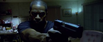 Movie still from “Miami Vice” (2006), directed by Michael Mann – A man holding a gun in a room; Close Up shot, Low angle