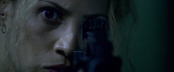 Movie still from “Miami Vice” (2006), directed by Michael Mann – A woman's face with a gun in her hand; Extreme Close Up shot, Over the shoulder angle
