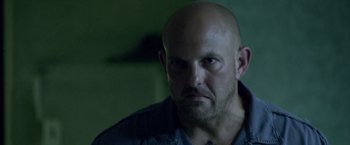 Movie still from “Miami Vice” (2006), directed by Michael Mann – A man with a bald head stares into the camera; Close Up shot, Low angle