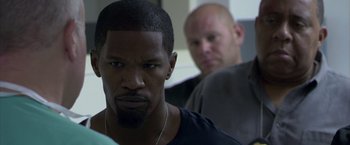 Movie still from “Miami Vice” (2006), directed by Michael Mann – A man standing next to another man in a room; Close Up shot, Over the shoulder angle