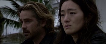 Movie still from “Miami Vice” (2006), directed by Michael Mann – A man and a woman sitting next to each other in front of trees; Close Up shot, Low angle