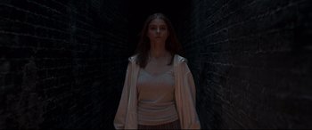Movie still from “Last Night in Soho” (2021), directed by Edgar Wright – A woman standing in a dark room wearing a white shirt; Medium shot, Low angle