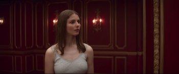 Movie still from “Last Night in Soho” (2021), directed by Edgar Wright – A beautiful young lady standing next to a red wall; Medium shot, Over the shoulder angle