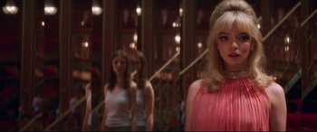Movie still from “Last Night in Soho” (2021), directed by Edgar Wright – A woman in a pink dress standing next to another woman in a pink dress; Close Up shot, Over the shoulder angle