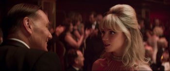 Movie still from “Last Night in Soho” (2021), directed by Edgar Wright – A group of people standing in a room; Close Up shot, Over the shoulder angle