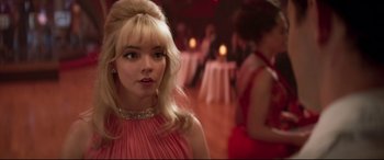 Movie still from “Last Night in Soho” (2021), directed by Edgar Wright – A woman in a pink dress standing in front of a crowd; Close Up shot, Over the shoulder angle