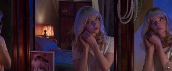 Movie still from “Last Night in Soho” (2021), directed by Edgar Wright – A woman with blonde hair is holding her hand to her face; Medium shot, Over the shoulder angle