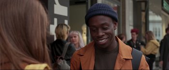 Movie still from “Last Night in Soho” (2021), directed by Edgar Wright – A young man smiles while standing on the sidewalk; Close Up shot, Over the shoulder angle