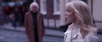 Movie still from “Last Night in Soho” (2021), directed by Edgar Wright – A woman standing in front of a man in front of a building; Close Up shot, Over the shoulder angle
