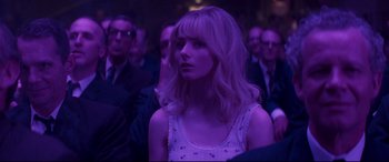 Movie still from “Last Night in Soho” (2021), directed by Edgar Wright – A woman in a white dress sitting in front of a group of people; Medium shot, Over the shoulder angle