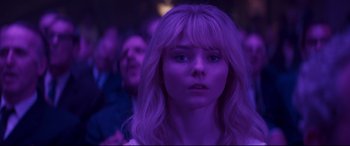 Movie still from “Last Night in Soho” (2021), directed by Edgar Wright – A woman with blue eyes and blonde hair in front of a group of people; Close Up shot, Low angle