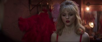 Movie still from “Last Night in Soho” (2021), directed by Edgar Wright – A woman in a red dress is standing in front of some red feathers; Close Up shot, Over the shoulder angle