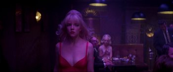 Movie still from “Last Night in Soho” (2021), directed by Edgar Wright – A woman in a red dress standing in front of other people; Medium shot, Over the shoulder angle