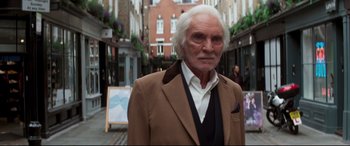 Movie still from “Last Night in Soho” (2021), directed by Edgar Wright – An older man in a brown jacket standing on the street; Medium shot, High angle