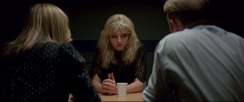 Movie still from “Last Night in Soho” (2021), directed by Edgar Wright – A woman sitting at a table with two other people; Medium shot, Over the shoulder angle