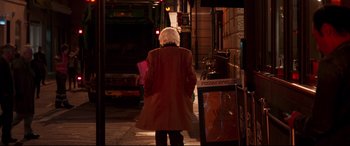 Movie still from “Last Night in Soho” (2021), directed by Edgar Wright – A woman in a red coat walking down a street; Wide shot, Over the shoulder angle
