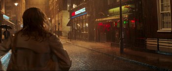 Movie still from “Last Night in Soho” (2021), directed by Edgar Wright – A person walking down a street in the rain; Wide shot, Over the shoulder angle