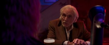 Movie still from “Last Night in Soho” (2021), directed by Edgar Wright – An older man sitting at a table with a glass of beer in front of him; Close Up shot, Over the shoulder angle