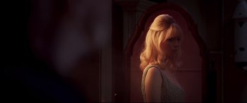 Movie still from “Last Night in Soho” (2021), directed by Edgar Wright – A woman with blonde hair is standing in a room; Medium shot, Over the shoulder angle