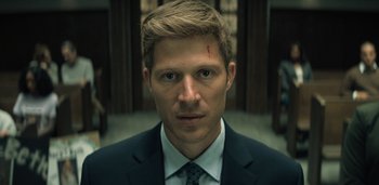 Movie still from “Midnight Mass” (2021), directed by Mike Flanagan – A person wearing a suit and tie; Close Up shot, Low angle