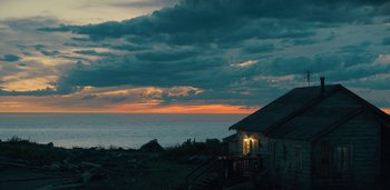 Movie still from “Midnight Mass” (2021), directed by Mike Flanagan – A house on the shore of a body of water at sunset; Extreme Wide shot, High angle