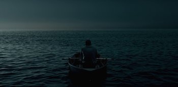 Movie still from “Midnight Mass” (2021), directed by Mike Flanagan – A man sitting in a boat in the middle of the ocean; Extreme Wide shot, High angle