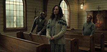 Movie still from “Midnight Mass” (2021), directed by Mike Flanagan – A woman standing in front of a man in a church; Medium shot, Low angle