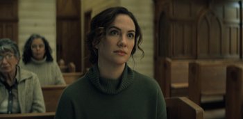 Movie still from “Midnight Mass” (2021), directed by Mike Flanagan – A woman in a green sweater looking to her left; Close Up shot, Over the shoulder angle