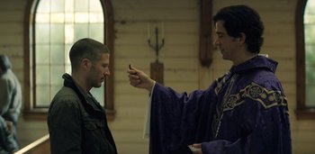 Movie still from “Midnight Mass” (2021), directed by Mike Flanagan – A priest is pointing to a man in front of him; Medium shot, Low angle