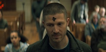 Movie still from “Midnight Mass” (2021), directed by Mike Flanagan – A person with a cross on his forehead; Close Up shot, High angle