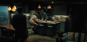 Movie still from “Midnight Mass” (2021), directed by Mike Flanagan – Two men are sitting at a kitchen counter; Wide shot, High angle