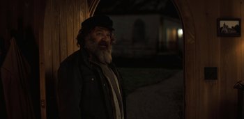 Movie still from “Midnight Mass” (2021), directed by Mike Flanagan – An old man with a beard and a black hat; Medium shot, Over the shoulder angle