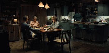 Movie still from “Midnight Mass” (2021), directed by Mike Flanagan – A group of people sitting at a table in a kitchen; Wide shot, High angle