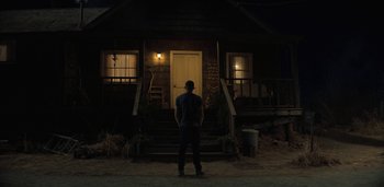 Movie still from “Midnight Mass” (2021), directed by Mike Flanagan – A man standing in front of a house at night; Wide shot, Low angle